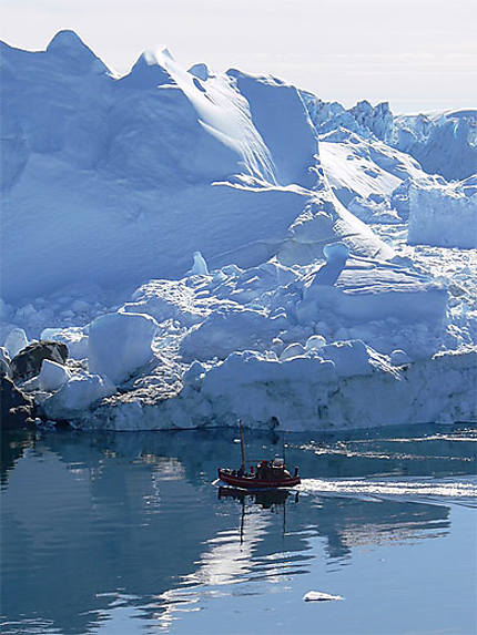 Bateau de pêcheur devant un iceberg géant au Groenland 
