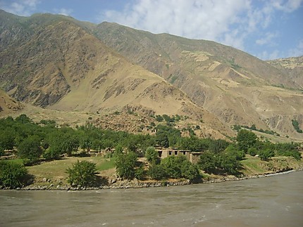Village Afghan au delà de la rivière Panj