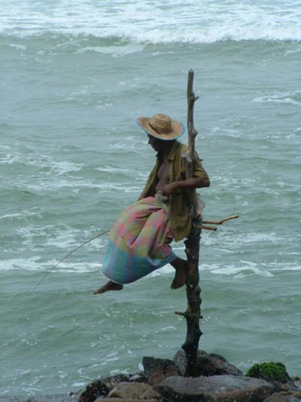 Pêcheur assis sur un poteau