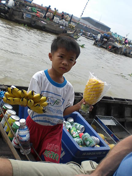 Marchés flottants enfant vendant en bateau 